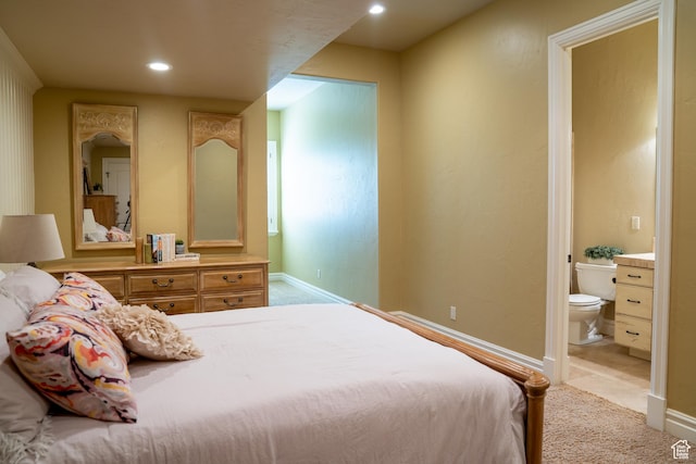 bedroom with light carpet, ensuite bathroom, and baseboards