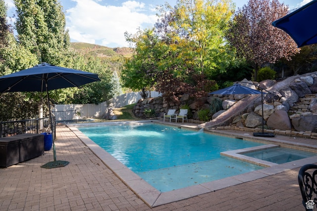 view of swimming pool with a patio area, a water slide, a fenced backyard, an in ground hot tub, and a fenced in pool