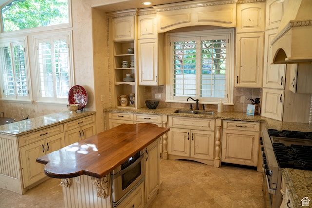 kitchen with butcher block countertops, decorative backsplash, a sink, and built in microwave