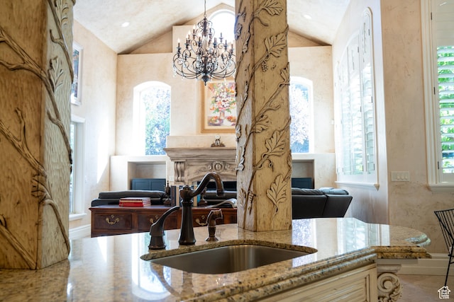 kitchen with light stone counters, a sink, lofted ceiling, and a wealth of natural light