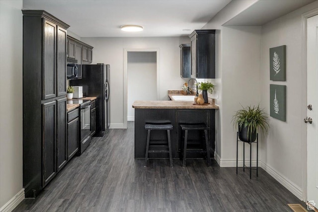 783 W 900 S, Tremonton, UT 84337 - kitchen with dark wood finished floors, black electric range oven, a breakfast bar area, and baseboards