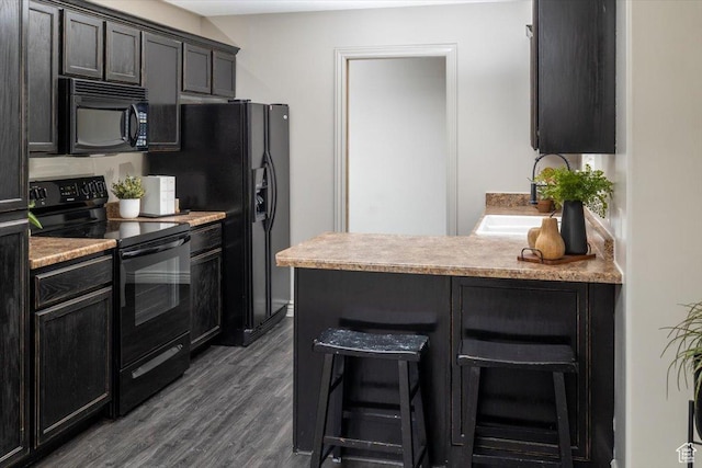 783 W 900 S, Tremonton, UT 84337 - kitchen with light countertops, a kitchen breakfast bar, dark wood-style floors, black appliances, and a sink