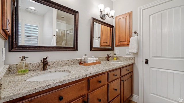 bathroom with a sink, double vanity, a notable chandelier, and a shower with door