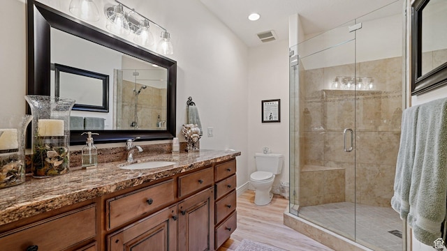 full bathroom featuring toilet, a shower stall, visible vents, and wood finished floors