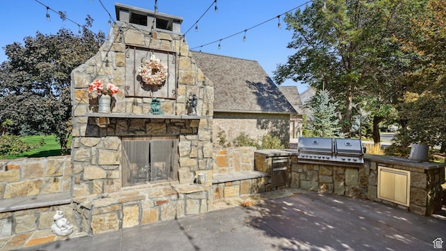 view of patio / terrace with an outdoor stone fireplace, grilling area, and exterior kitchen