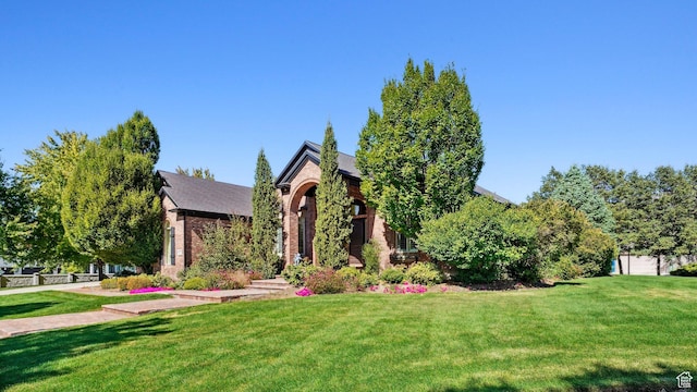 tudor home featuring brick siding and a front lawn
