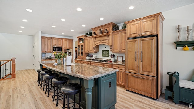 kitchen with a kitchen island with sink, appliances with stainless steel finishes, light stone countertops, and recessed lighting