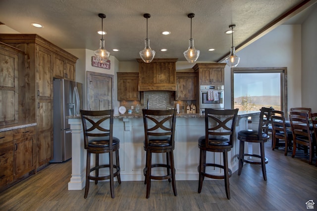 86 Aster Pl, Fish Haven, ID 83287 - kitchen featuring a kitchen bar, appliances with stainless steel finishes, hanging light fixtures, and dark wood-type flooring