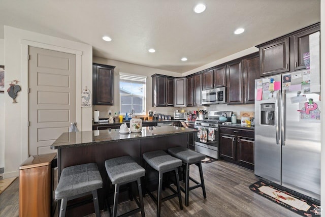 665 S 1400 W, Syracuse, UT 84075 - kitchen featuring dark brown cabinets, a center island, appliances with stainless steel finishes, a breakfast bar area, and dark wood-style floors