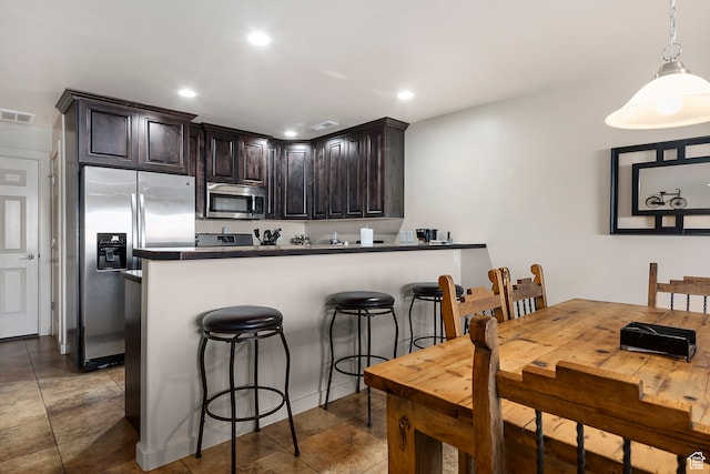 3862 Desert Willow Cir Unit A8, Moab, UT 84532 - kitchen featuring pendant lighting, dark brown cabinets, kitchen peninsula, a kitchen breakfast bar, and stainless steel appliances