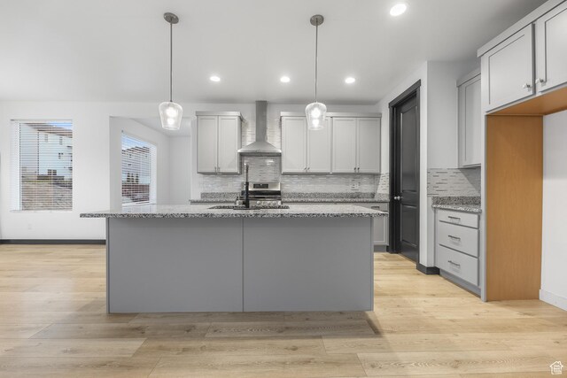 2867 S Greenhead Dr, Saratoga Springs, UT 84045 - kitchen featuring tasteful backsplash, wall chimney exhaust hood, a sink, and light stone counters