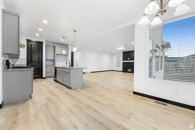 2867 S Greenhead Dr, Saratoga Springs, UT 84045 - kitchen featuring light wood-style flooring, visible vents, gray cabinets, a sink, and backsplash