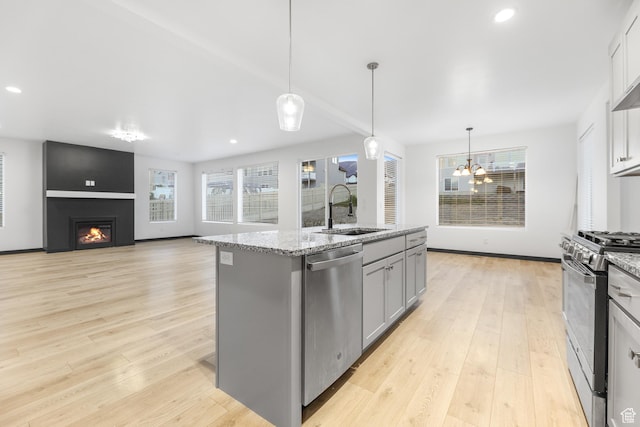 2867 S Greenhead Dr, Saratoga Springs, UT 84045 - kitchen with light wood-style floors, a large fireplace, a sink, stainless steel appliances, and gray cabinetry