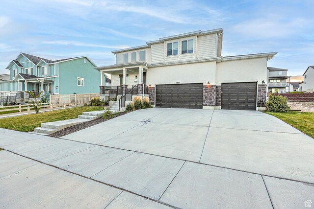 2867 S Greenhead Dr, Saratoga Springs, UT 84045 - view of front facade with covered porch, fence, stone siding, concrete driveway, and a residential view