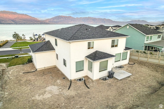 2867 S Greenhead Dr, Saratoga Springs, UT 84045 - rear view of house featuring stucco siding, fence, a shingled roof, and a water and mountain view