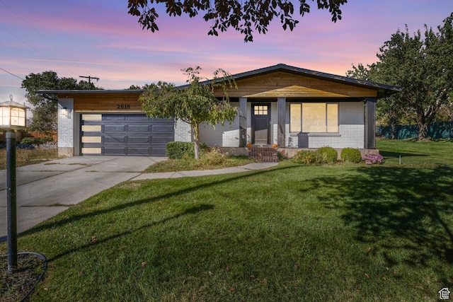 view of front of home featuring concrete driveway, an attached garage, brick siding, and a lawn