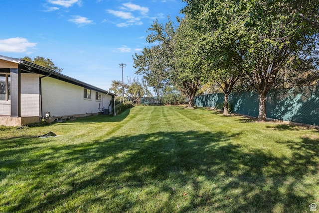 view of yard featuring central air condition unit and fence