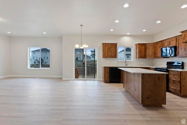1696 S Windsong Dr Unit 362, Santaquin, UT 84655 - kitchen with light wood-type flooring, black appliances, an inviting chandelier, a center island, and decorative light fixtures
