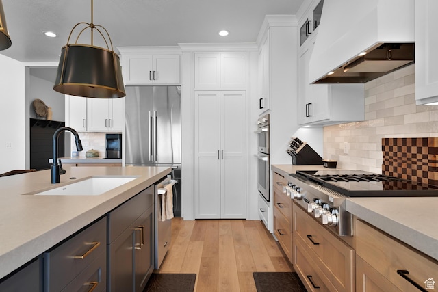 kitchen with recessed lighting, custom range hood, appliances with stainless steel finishes, light countertops, and a sink