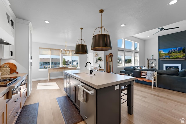 kitchen featuring light wood finished floors, a sink, a breakfast bar, light countertops, and appliances with stainless steel finishes