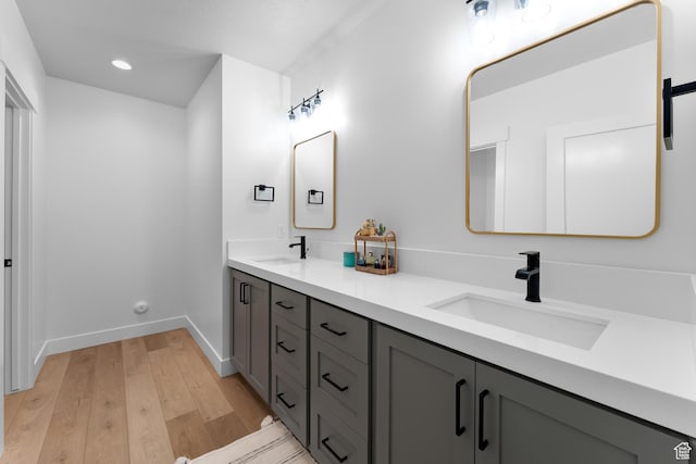 full bathroom featuring double vanity, a sink, wood finished floors, and baseboards