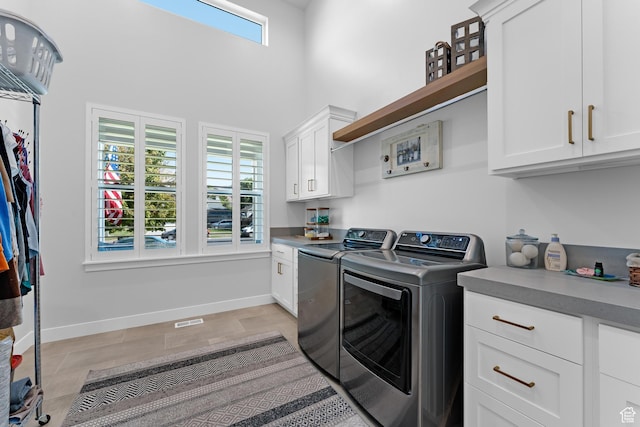 clothes washing area with cabinet space, washing machine and dryer, baseboards, visible vents, and a high ceiling