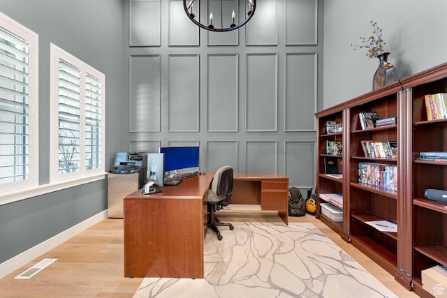 office space featuring visible vents, wood finished floors, a notable chandelier, and a decorative wall