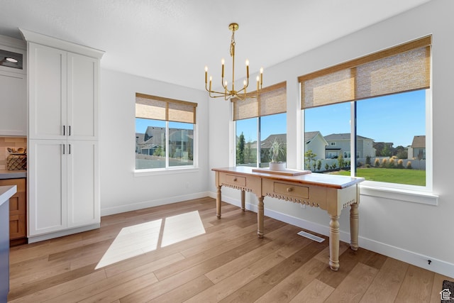 unfurnished dining area featuring visible vents, a notable chandelier, light wood-style flooring, and baseboards