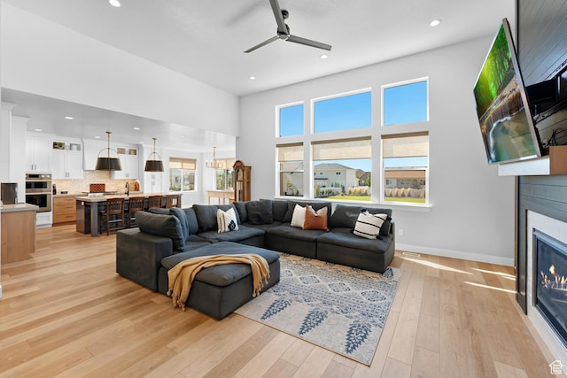 living area with a glass covered fireplace, a ceiling fan, and recessed lighting