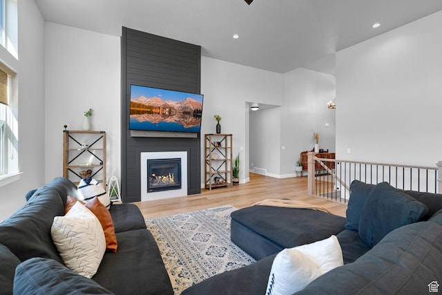 living area with a fireplace, light wood-style floors, recessed lighting, and baseboards