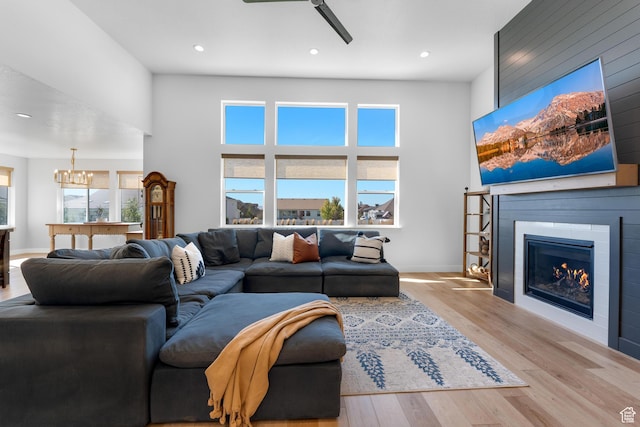 living room featuring a glass covered fireplace, wood finished floors, recessed lighting, and a high ceiling