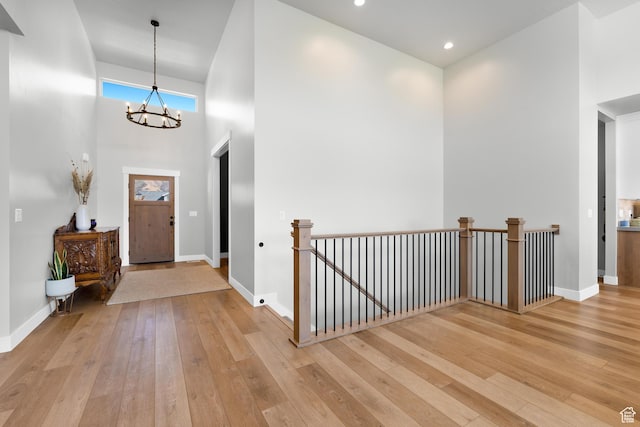 entrance foyer featuring a high ceiling, an inviting chandelier, light wood-style flooring, and baseboards