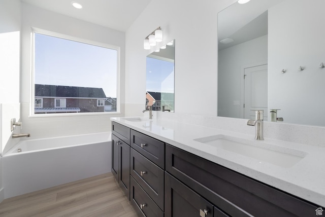 bathroom with hardwood / wood-style flooring, vanity, and a bathing tub
