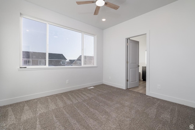 empty room featuring ceiling fan and carpet