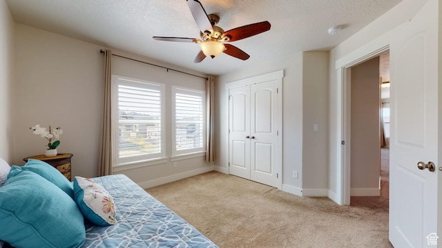 carpeted bedroom with baseboards, a ceiling fan, a textured ceiling, and a closet