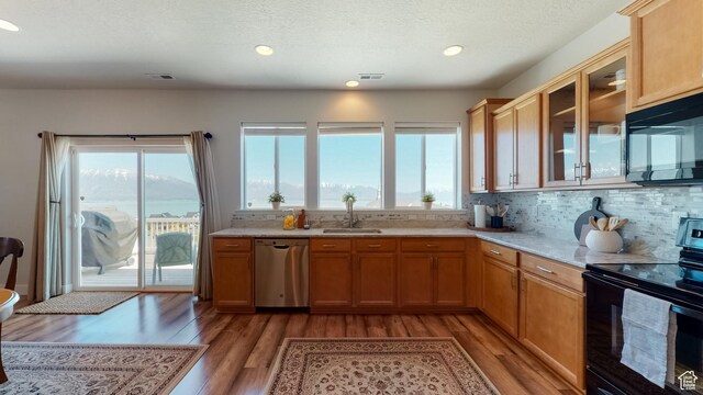 kitchen with visible vents, black appliances, light wood-style floors, and a sink