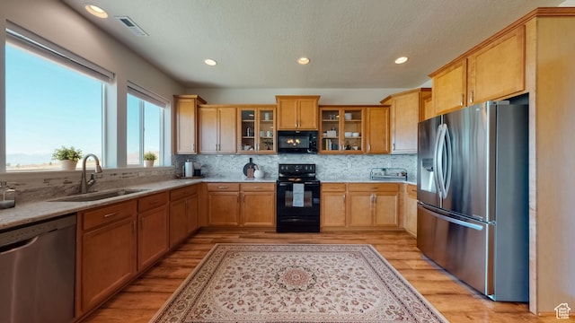 kitchen with light wood finished floors, recessed lighting, a sink, tasteful backsplash, and black appliances