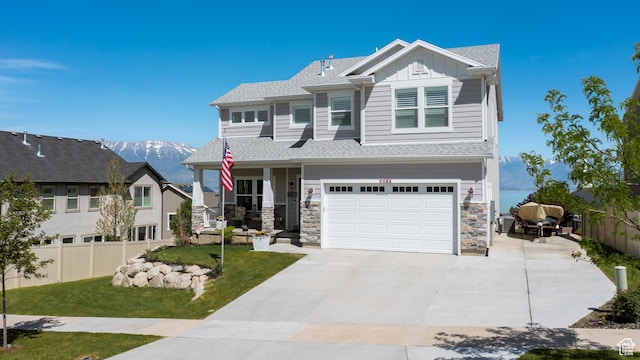 view of front of house featuring a front yard, a garage, driveway, board and batten siding, and fence