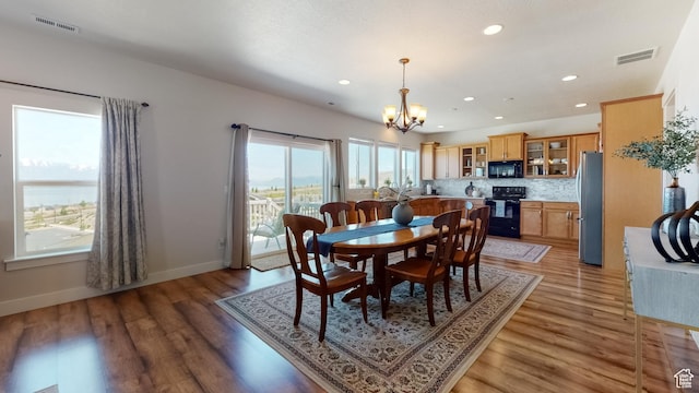 dining area featuring light wood-style flooring, visible vents, baseboards, recessed lighting, and a notable chandelier