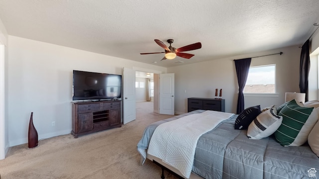 bedroom featuring light colored carpet, a ceiling fan, and a textured ceiling