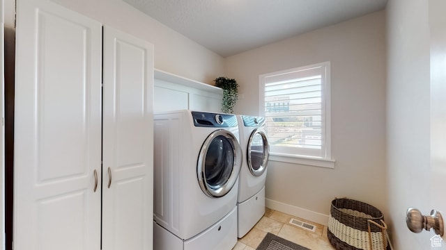 washroom featuring laundry area, light tile patterned floors, washing machine and clothes dryer, baseboards, and visible vents