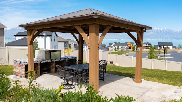 view of patio / terrace with a water and mountain view, a gazebo, outdoor dining area, and a fenced backyard