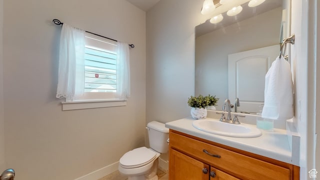 bathroom with baseboards, toilet, and vanity
