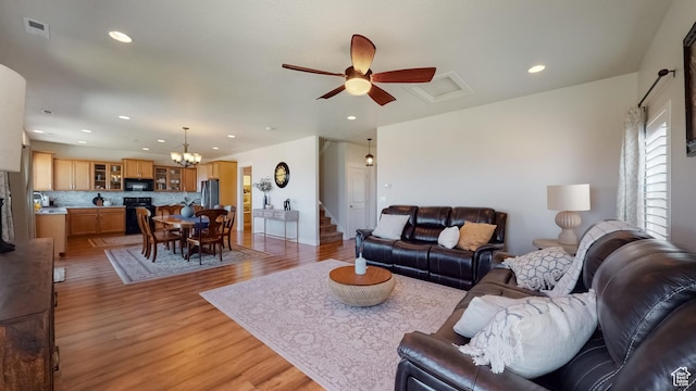 living area featuring recessed lighting, stairway, light wood-style floors, visible vents, and ceiling fan with notable chandelier