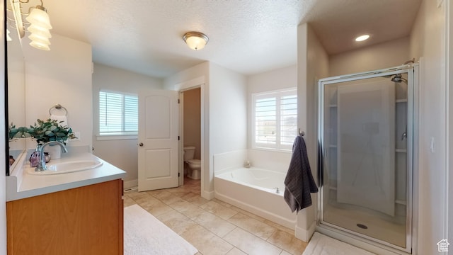bathroom with a stall shower, toilet, double vanity, and a sink