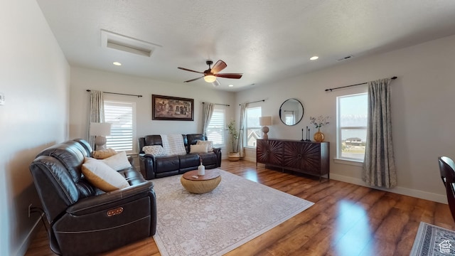 living area featuring attic access, a ceiling fan, visible vents, baseboards, and wood finished floors