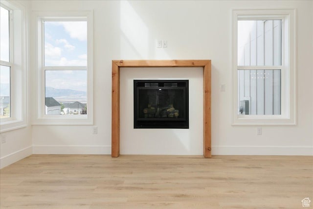 1153 E 160 N, Hyde Park, UT 84318 - unfurnished living room with light wood-type flooring, baseboards, and a glass covered fireplace