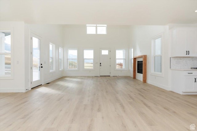 1153 E 160 N, Hyde Park, UT 84318 - unfurnished living room featuring a glass covered fireplace, light wood finished floors, and baseboards