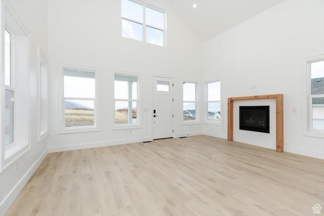 1153 E 160 N, Hyde Park, UT 84318 - unfurnished living room with light wood-type flooring, a fireplace, high vaulted ceiling, and a healthy amount of sunlight
