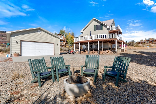 back of property featuring a fire pit, a garage, and a deck
